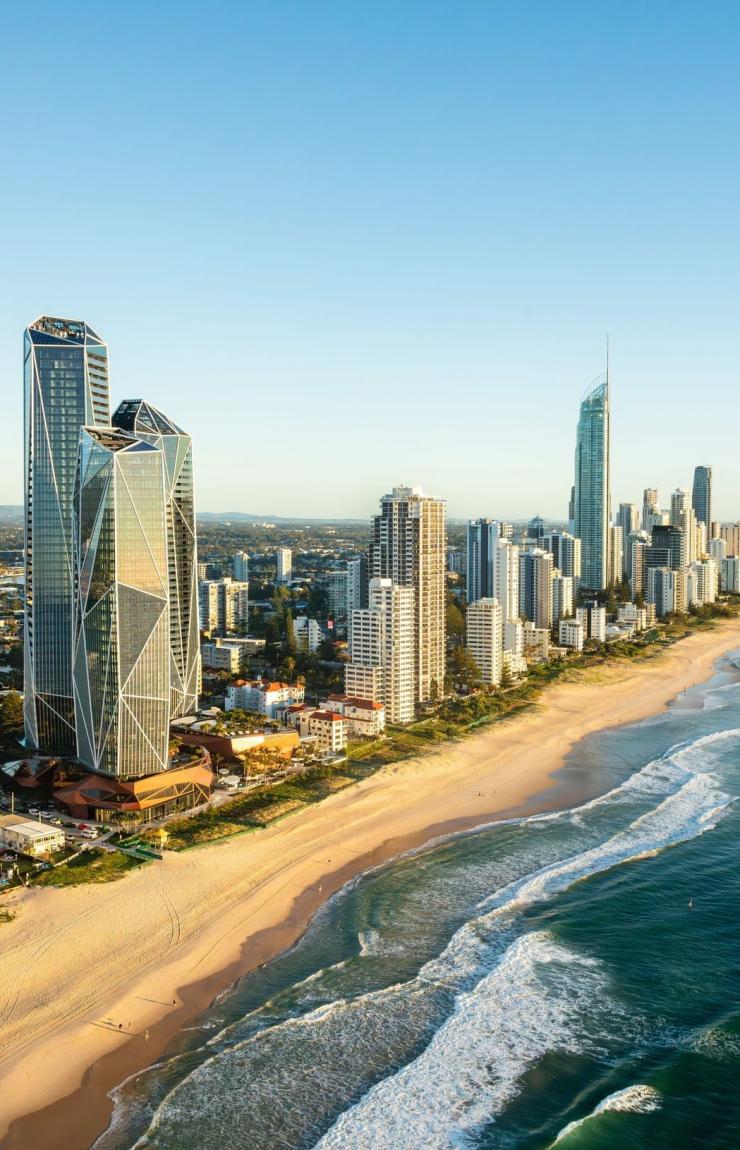 An aerial view over Surfers Paradise Beach captures a lively scene under bright sunshine, Gold Coast, Queensland © Tourism Australia
